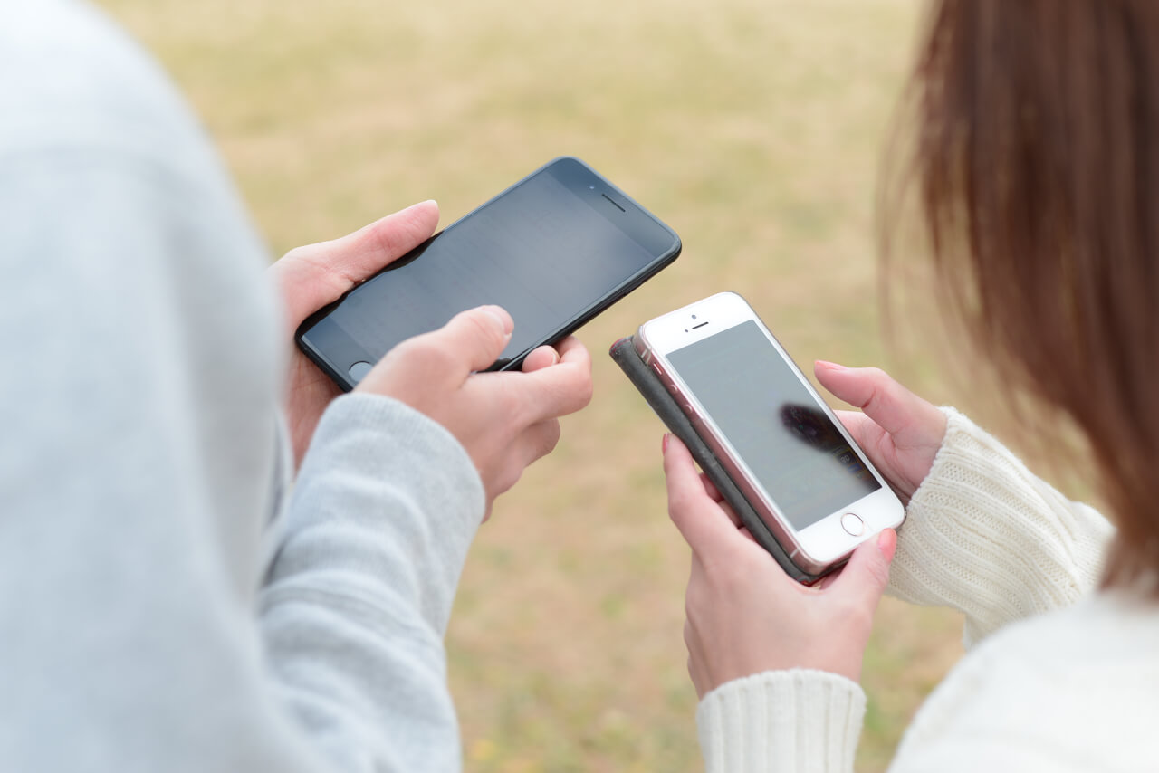 男女が隣り合ってスマホを扱っている様子