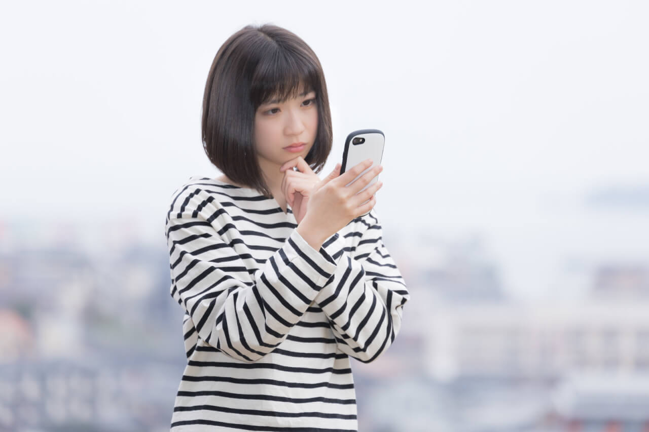 スマホを見ながら表情を曇らせている女性